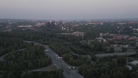 Vista-Aérea-De-Un-Gran-Complejo-Industrial-En-El-Centro-De-La-Ciudad-Rodeado-De-Bosque-Al-Atardecer.