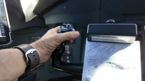 An-extreme-closeup-view-of-the-left-hand-of-white-pilot-wearing-a-watch-operating-the-control-wheel-inside-the-cockpit-of-a-modern-jet