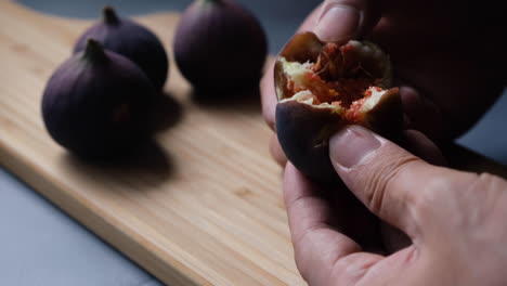 The-hands-of-Chef-open-fresh-fig-to-reveal-chewy-red-flesh-and-seeds-inside-in-the-kitchen