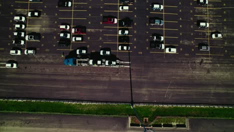 Aerial-view-over-a-car-carrier-trailer,-car-hauler-truck,-loading-with-new-cars-from-a-parking-lot