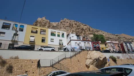 A-stunning-panoramic-view-showcases-colorful-homes-nestled-against-the-majestic-backdrop-of-Castel-De-Santa-Barbara-in-Alicante,-blending-vibrant-city-life-with-historic-charm