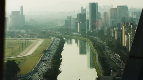 City-buildings-stretch-and-gleam,-reflected-in-the-river-water’s-dream