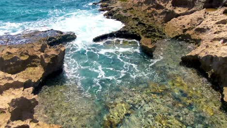 Agua-Brillante-Del-Océano-Y-Olas-Espumosas-Cerca-De-La-Costa-Rocosa,-Vista-Aérea