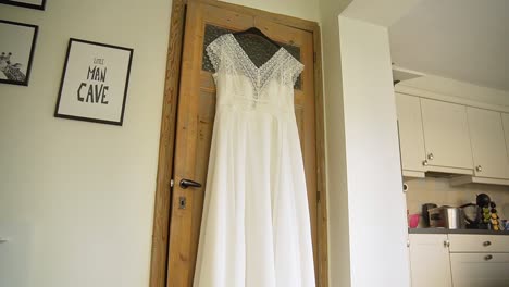 Elegant-wedding-dress-hanging-on-wooden-door-inside-modern-house