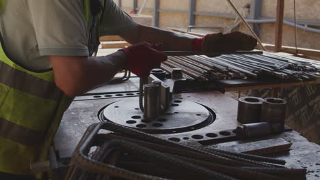 A-worker-is-seen-using-a-machine-to-bend-steel-rebars-on-a-construction-site