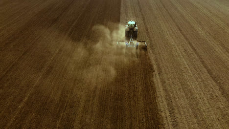 Tractor-cultivates-expansive-barren-fields,-aerial-shot