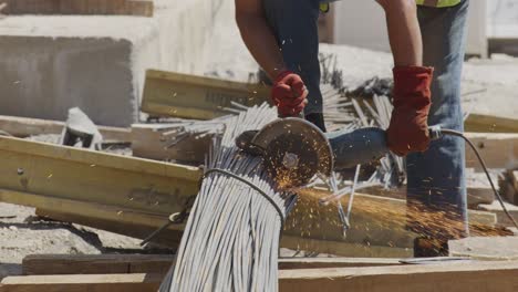 A-construction-worker-wearing-red-gloves-is-cutting-steel-rebars-using-an-angle-grinder,-producing-a-bright-shower-of-sparks