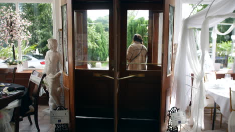 A-woman-walking-through-a-revolving-door,-exiting-a-well-decorated-hotel