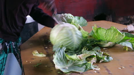 Person-chopping-fresh-cabbage-on-a-wooden-table-in-a-rustic-kitchen