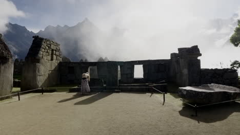 Tourist-woman-in-dress-walks-inside-Machu-Picchu-ruins-and-takes-photos