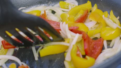 Colorful-Vegetables-Cooking-in-Very-Hot-Frying-Pan-with-Onions,-Peppers-in-Olive-Oil-Bubbling-as-Chef-Turns-Using-Spatula-Outside