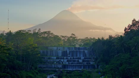 Watu-Purbo-waterfall-with-Merapi-volcano-in-background,-aerial-view