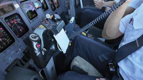 Left-view-inside-a-jet-cockpit-of-a-pilot-using-the-hand-microphone-to-address-the-passengers