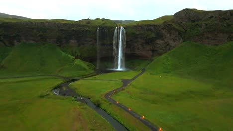 Diese-Drohnenaufnahmen-Fangen-Die-Magie-Des-Seljalandsfoss-Ein-Und-Zeigen-Seine-Einzigartigen-Aussichtspunkte-Und-Die-üppige-Landschaft,-Die-Ihn-Umgibt