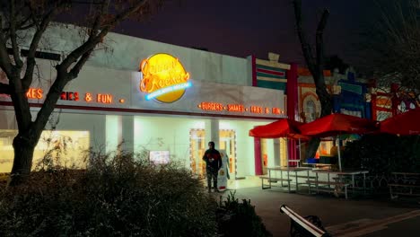 Truck-right-revealing-of-Johnny-Rockets-sign-at-night,-old-American-restaurant-theme,-Santiago,-Chile