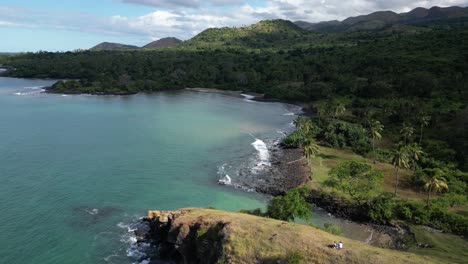 Aerial-view-of-a-tropical-bay-surrounded-by-lush-green-hills-and-palm-trees