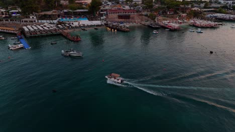 A-boat-glides-across-Ksamil's-tranquil-waters-during-a-colorful-sunset-with-distant-shoreline-views