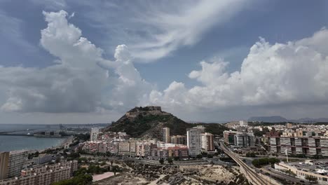 Panoramic-time-lapse-left-to-right-of-Alicante-City,-Spain,-with-a-view-of-the-city-center,-the-castle-and-Mediterranean-sea-in-a-summer-day-with-some-clouds-in-a-blue-sky