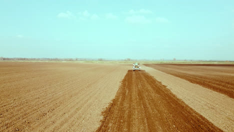 Tractor-operates-across-wide-agricultural-fields,-high-angle-shot