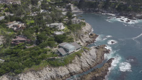 4K-aerial-view-of-cliff-side-homes-and-cove-with-PCH-in-the-background-in-the-Carmel-Highlands-California