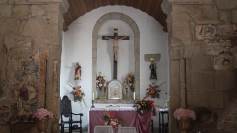 serene-altar-setup-in-a-stone-chapel-with-a-crucifix-and-flower-arrangements