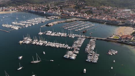 Aerial-view-of-Baiona-marina-with-boats-lined-up-in-the-water,-bordered-by-the-village