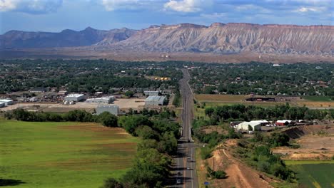 Summer-Grand-Mesa-downtown-Main-Street-Grand-Junction-Colorado-river-aerial-drone-forward-pan-up-motion-afternoon-cloudy-blue-sky-wine-vineyards-Parachute-Fruitvale-Mt-Garfield-Western-Close-Delta-USA