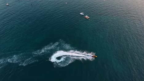 A-jet-ski-creates-a-splash-in-the-calm-waters-of-Ksamil,-Albania,-during-a-peaceful-sunset