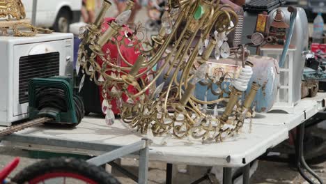 A-vintage,-gold-colored-metallic-chandelier-and-other-antique-items-are-elegantly-displayed-at-the-flea-market,-attracting-attention-with-its-timeless-charm-and-character