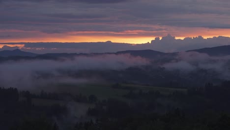 The-misty-hills-are-bathed-in-the-warm-light-of-the-setting-sun,-creating-a-peaceful-countryside-scene-as-the-darkness-falls-over-the-landscape