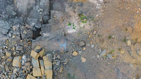 Aerial-top-down-view-of-unmanned-drone-fly-above-rocky-surface,-Czechia