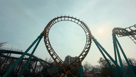 Toma-De-Mano-Desde-Una-Curva-Invertida,-Montaña-Rusa-De-Alta-Velocidad-Que-Gira-Sobre-Rieles,-Día-Soleado-En-Un-Parque-De-Diversiones