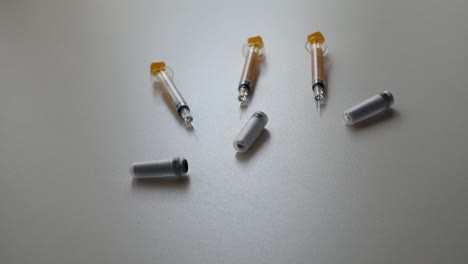 Pan-shot-of-syringes-and-containers-on-flat-surface