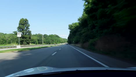 A-quiet-countryside-road-bordered-by-lush-green-trees-and-a-bright-blue-sky