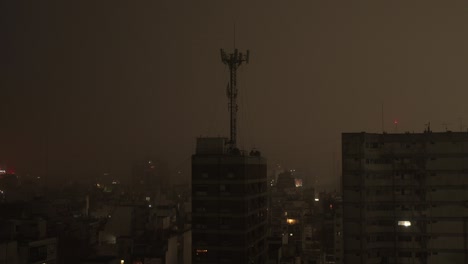 Cell-tower-stands-over-Buenos-Aires-cityscape-at-night,-surrounded-by-faint-urban-lights