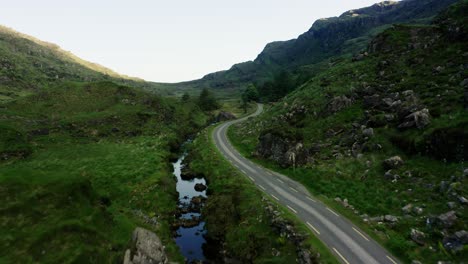 Drone-shot-of-a-road-winding-through-Ireland's-beautiful-outdoors