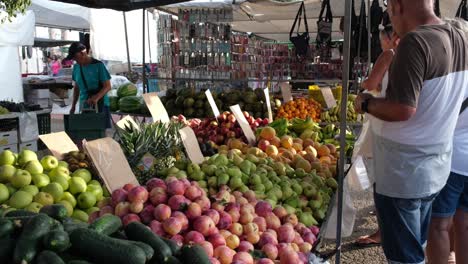 At-the-open-space-market,-people-eagerly-pick-and-select-fresh-fruits-and-vegetables,-exploring-vibrant-stalls-filled-with-seasonal-produce-and-enjoying-the-lively-atmosphere