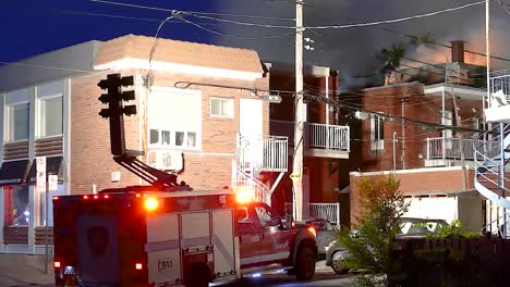 Firetruck-moving-lights-to-building-as-firefighters-work-during-night-on-street-in-Montreal,-Quebec