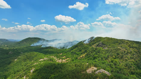 Establishing-drone-shot-of-hills-on-fire,-smoke-rising-from-smoldering-forest