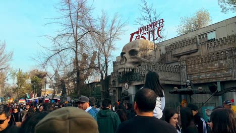 Panoramic-view-establishing-the-haunted-castle-totally-full-of-people,-Fantasilandia-amusement-park-in-Santiago,-Chile