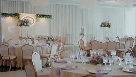 Lavender-accented-wedding-tables-arranged-with-fine-glassware,-floral-centerpieces,-and-gold-chairs