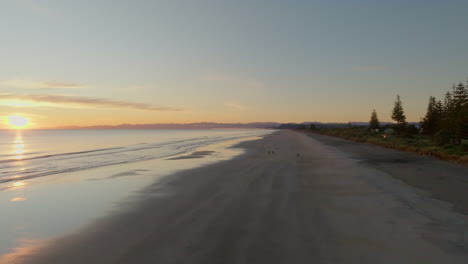 Rising-over-Ohope-Beach-at-sunrise,-Whakatane,-New-Zealand