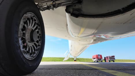 External-view,-extreme-low-angle,-of-the-lower-part-of-the-fuselage-and-wheels-of-a-white-color-fuselage-jet-parked-on-the-ramp-in-a-bright-sunny-day