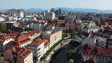 Aerial-drone-view-of-the-wonderful-city-of-Ljubljana-on-a-summer's-morning-with-city-and-mountains-in-background-and-Tromostovje-bridge