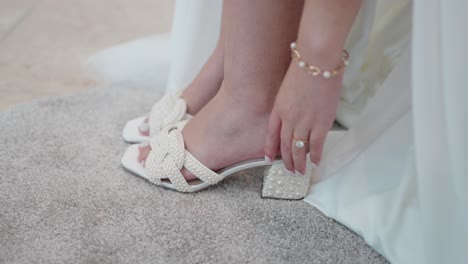 Close-up-of-a-bride's-foot-wearing-a-delicate-white-wedding-heel-with-pearl-details,-ready-for-the-ceremony