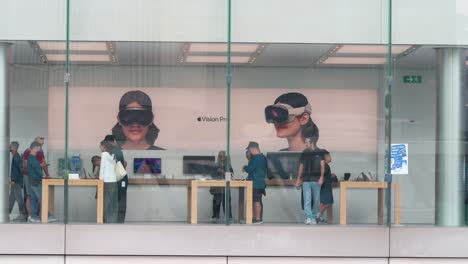 While-customers-browse-for-Apple-products-at-the-store-of-the-American-tech-giant,-a-poster-displaying-the-Apple-Vision-Pro,-the-company's-new-mixed-reality-headset,-can-be-seen-in-the-background