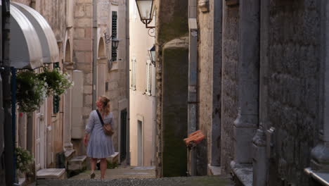 Blonde-in-dress-walk-in-idyllic-narrow-old-town-street-in-Herceg-Novi-Montenegro