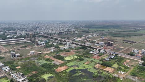 Drone-view-of-a-road-flanked-by-green-farmland,-stretching-into-the-horizon