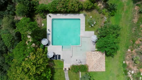 Top-down-aerial-view-of-an-outdoor-swimming-pool-at-Domaine-Sainte-Colombe,-France,-highlighting-its-design-and-surroundings,-ideal-for-concepts-of-luxury,-relaxation,-and-upscale-leisure