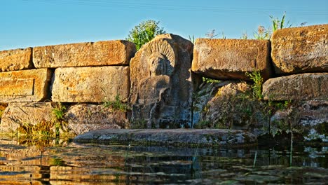 An-ancient-stone-carving-at-the-Holy-Water-Temple,-where-the-intricate-design-of-a-figure-is-etched-into-the-weathered-rock